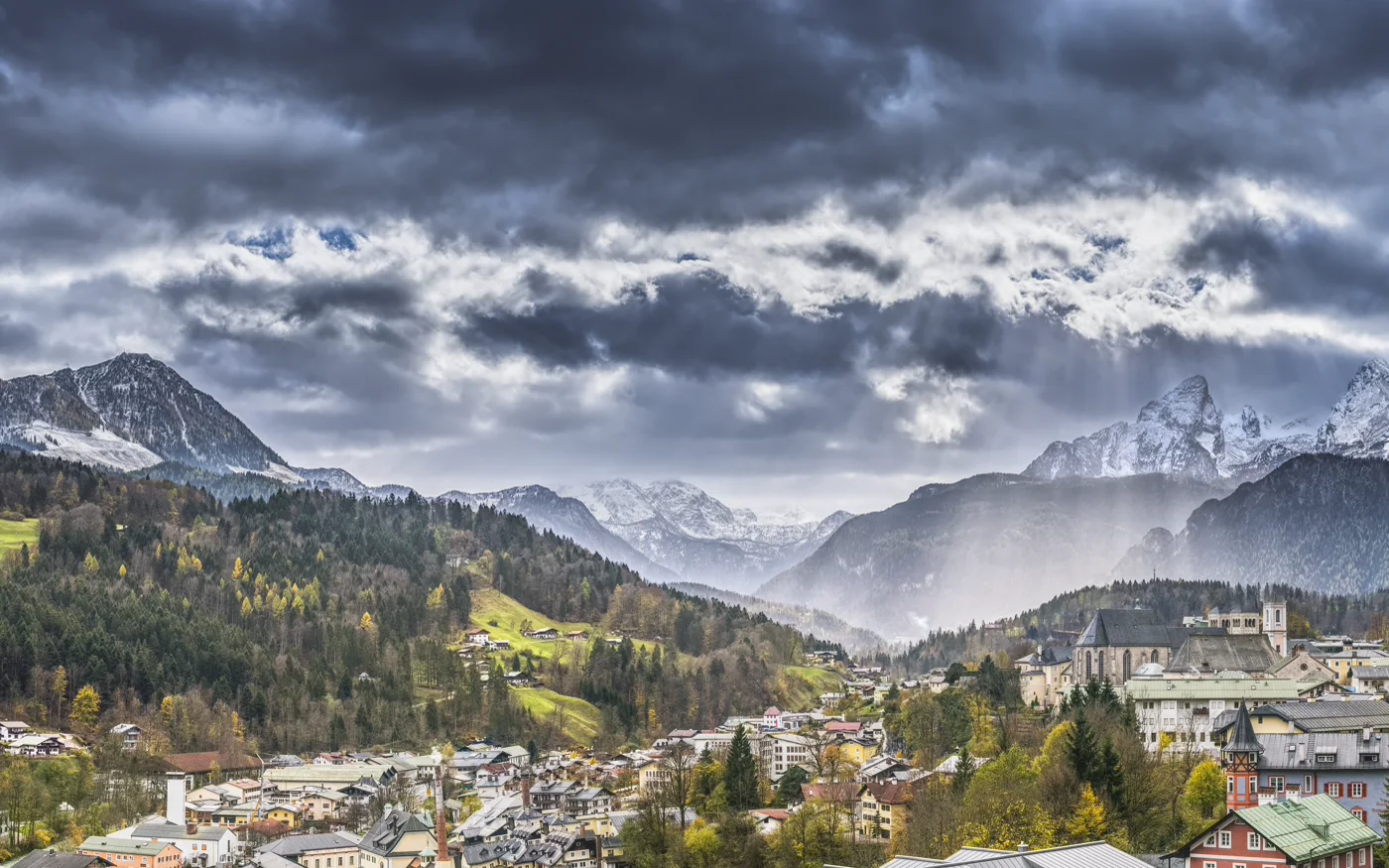 Blick über Berchtesgaden mit Stiftskirche und Watzmannmassiv unter dunklen Wolken