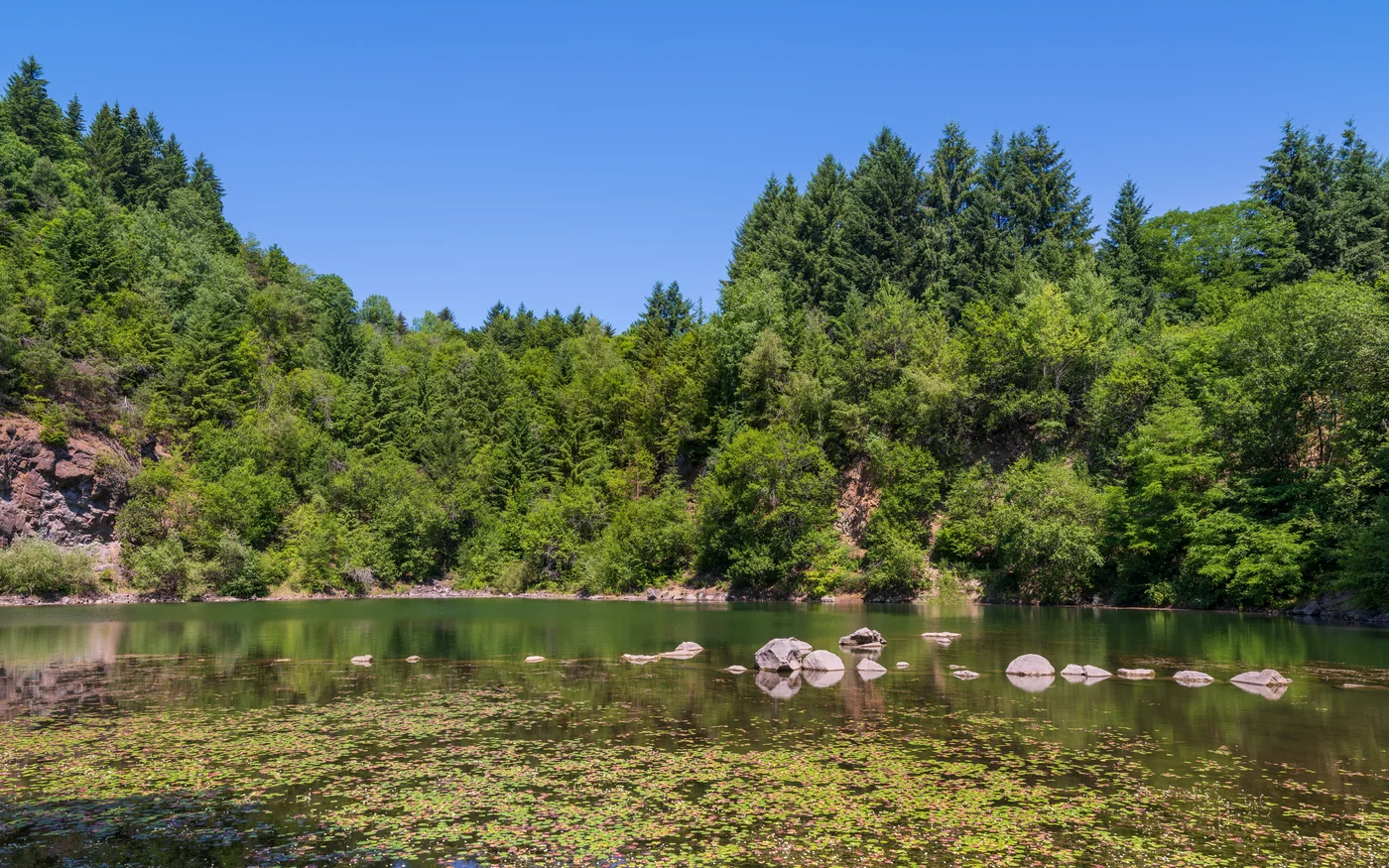 Katzenbuckelsee mit bewaldeter Felswand des ehemaligen Steinbruchs unterhalb des Katzenbuckelgipfels