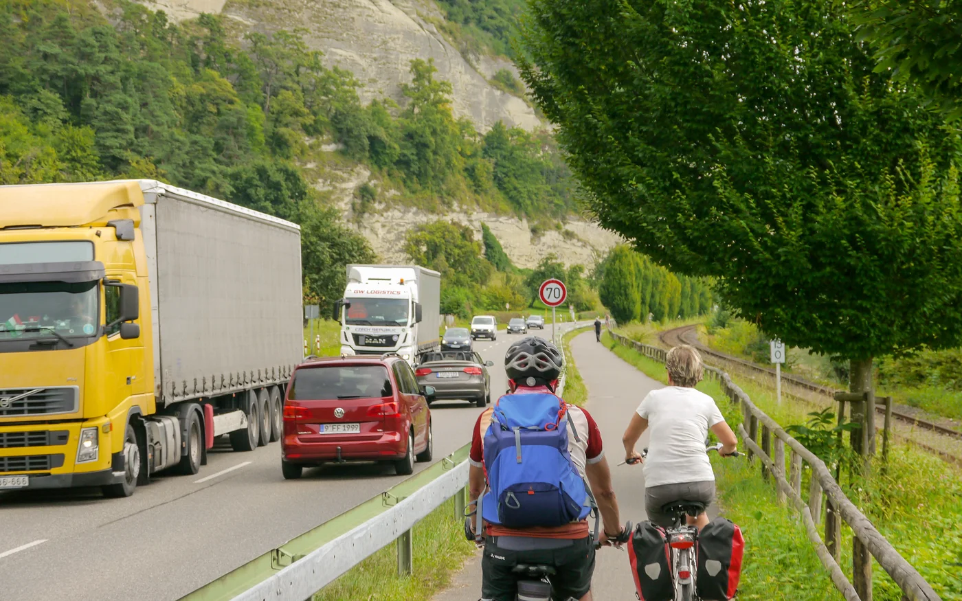 Zwei Radreisende auf einem schmalen Radweg neben dichtem Auto- und Lastwagenverkehr vor Überlingen